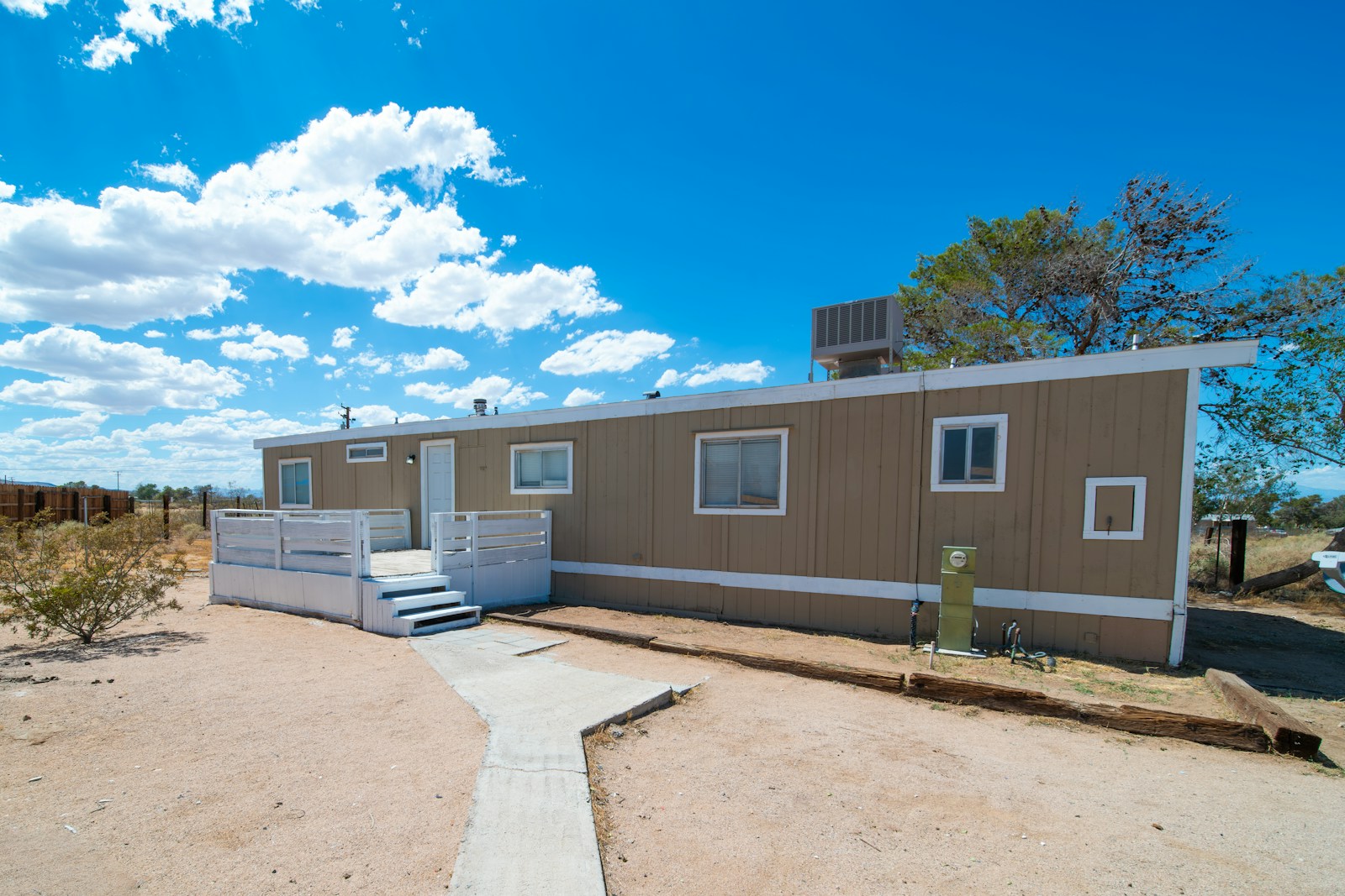 a couple of small houses sitting on top of a dirt field, mobile home